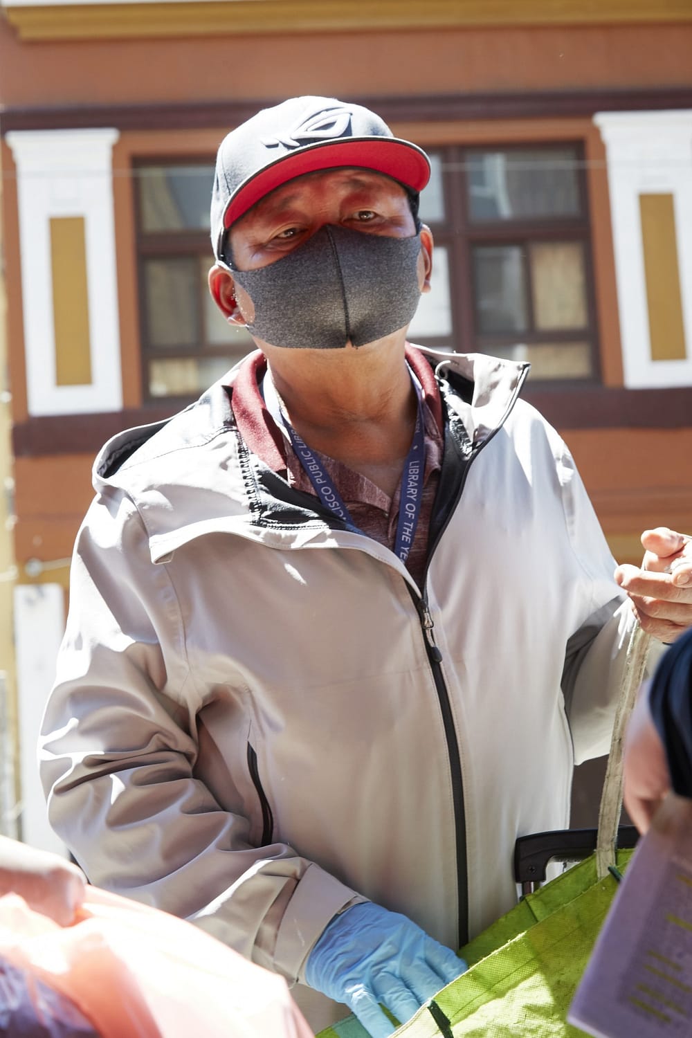 Southeast Asian American male elder wearing a facemask and rubber gloves during a covid-19 food drive in tenderloin, san francisco